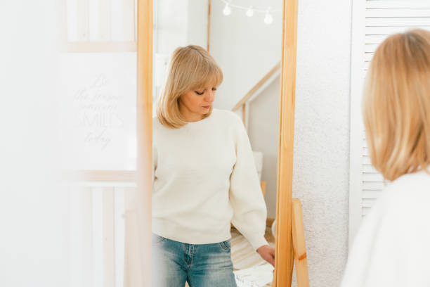 istock woman standing near mirror and looking at reflection 1312675047