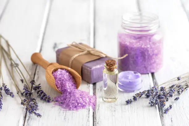 Lavender spa products on an old white wooden table. Body care products with lavender-oil, salt, cream, soap and dried lavender flowers. Selective focus