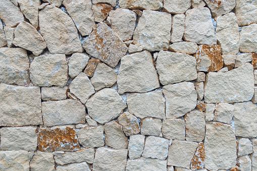 Masonry wall of stones with irregular pattern texture background.