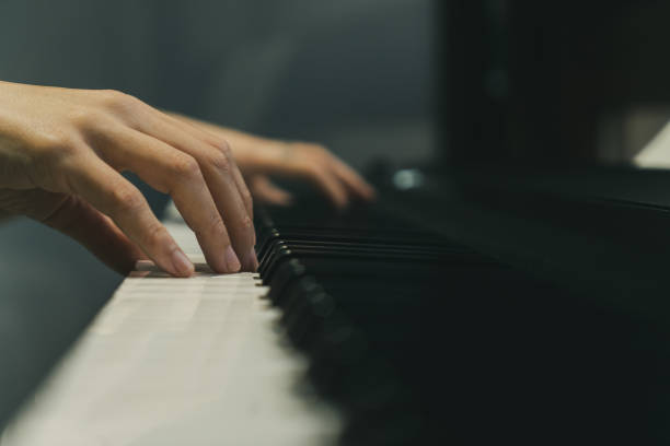 frau spielt ein lied auf ihrem klavier - piano keyboard instrument one person piano key stock-fotos und bilder