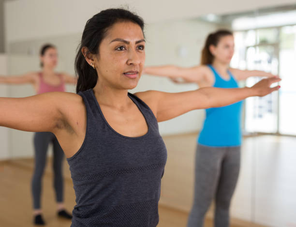 istock Hispanic woman doing warmup during group workout at gym 1312682814