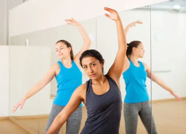 Photo of Hispanic woman practicing classic dance moves during group class