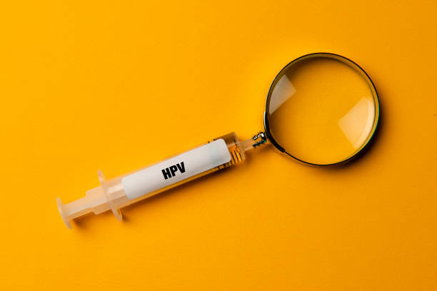 HPV Research Syringe-shaped magnifier. Magnifying glass and HPV syringe on yellow background. human papilloma virus photos stock pictures, royalty-free photos & images