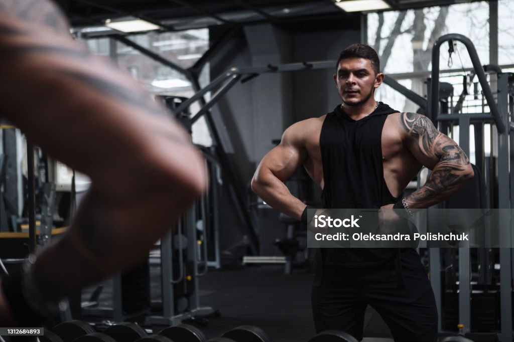 Ripped bodybuilder exercising at the gym Professional bodybuilding athlete posing at the gym in front of the mirror Body Building Stock Photo