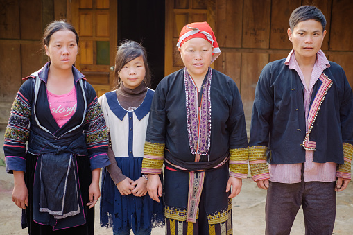 Sapa, Vietnam - April 15: Portrait of Red Dzao ethnic minority family in traditional clothes. Husband, wife and daughter near the traditional home.