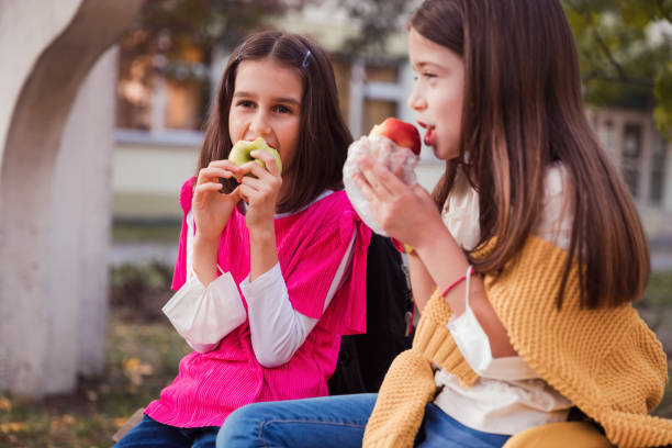 istock Cheerful girls eating fruit for a snack 1312690463