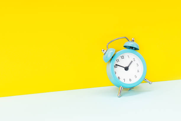 istock blue alarm clock over yellow background. studio shot. time concept. template for design 1312690684