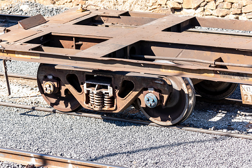 Old and rusty train wheels on a flat bed carriage sitting idle on railway tracks at a production facility loading bay