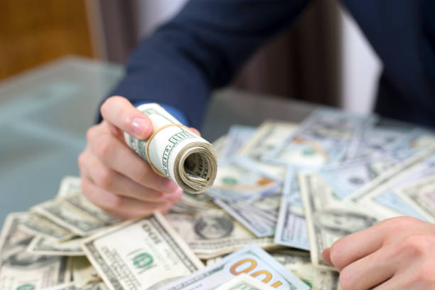 istock Business Man looking over a pile of assorted U.S bills. 1312694326