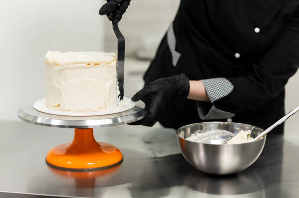 istock woman pastry chef in uniform prepares cake 1312695499