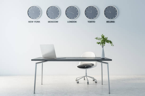 istock Different cities time on wall clock in modern light cabinet with laptop on marble table and concrete floor 1312698906