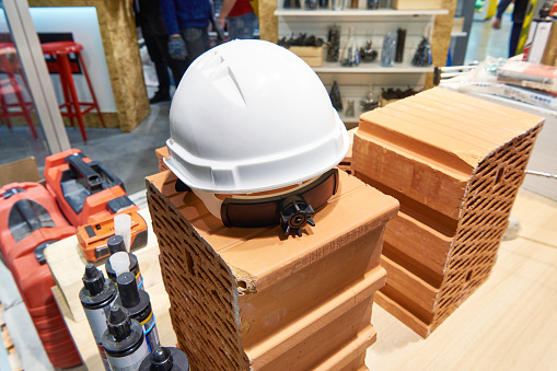 Builder safety helmet, tools and bricks in a building materials store