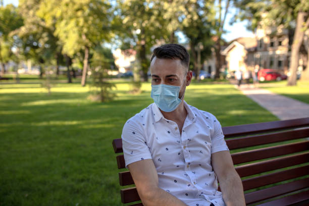 istock The young man is sitting in the park with a protective mask 1312702721
