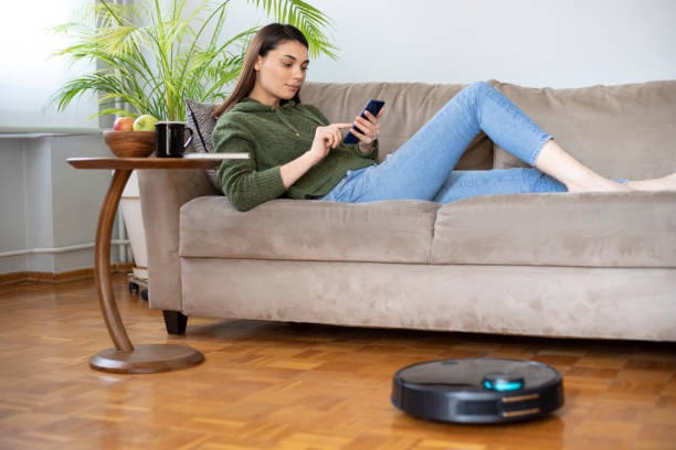 istock young beautiful housewife using cleaning robot at home, relaxing on sofa 1312705408