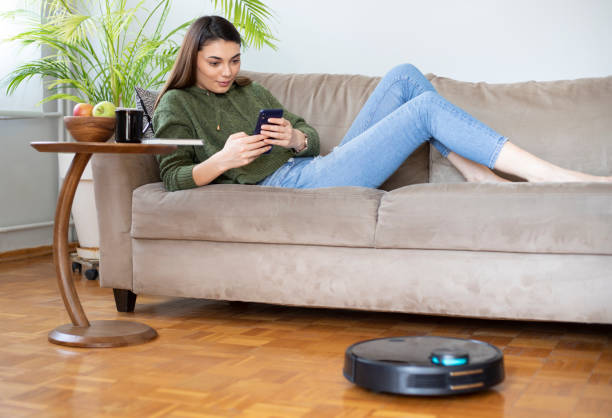 istock young beautiful housewife using cleaning robot at home, relaxing on sofa 1312705465