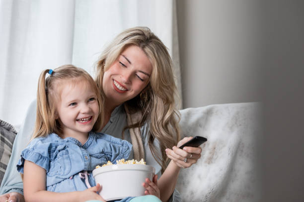 istock Mother and daughter smile while watching tv together 1312706283