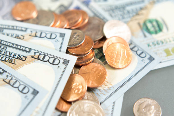 istock Several Hundred dollar bills and coins laying on a table 1312717252