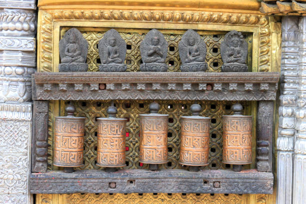 Metal prayer wheels with carved deities at a temple Metal prayer wheels with carved deities at a temple in Kathmandu, Nepal prayer wheel nepal kathmandu buddhism stock pictures, royalty-free photos & images
