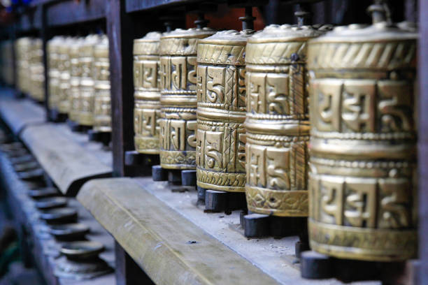 Row of traditional prayer wheels at temple Row of traditional prayer wheels at temple in Nepal buddhist prayer wheel stock pictures, royalty-free photos & images
