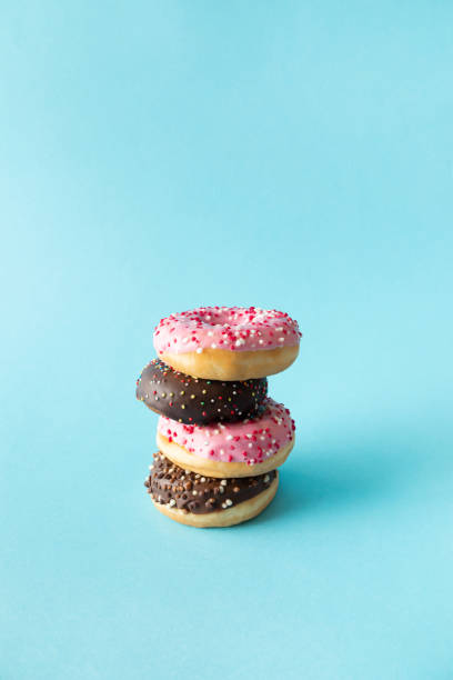 Strawberry and chocolate doughnuts with sprinkles. Pastel cyan background.