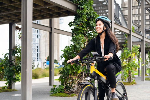 Young Eurasian woman riding electric bike to work.