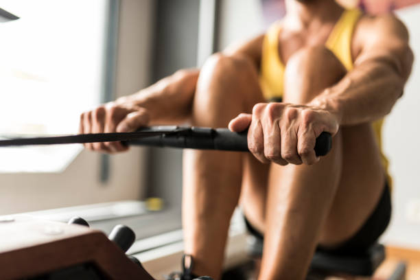 Close up image of anonymous man training in rowing exercise machine stock photo