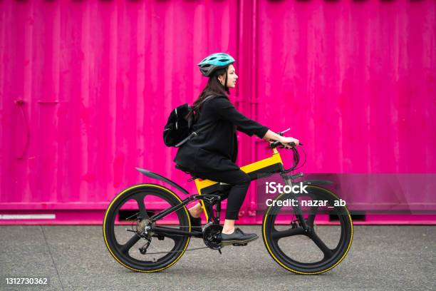 Young Woman Riding Electric Bike With Pink Background Stock Photo - Download Image Now