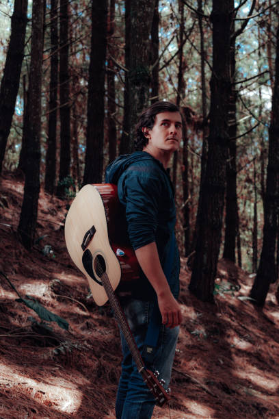 istock Model playing guitar in the middle of a forest 1312730424