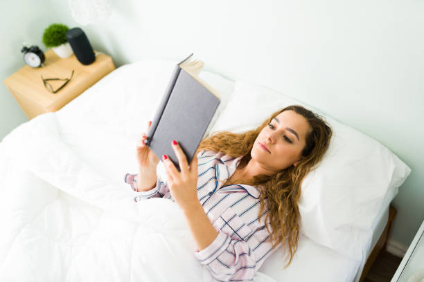 istock Attractive woman relaxing in bed with a book 1312734545