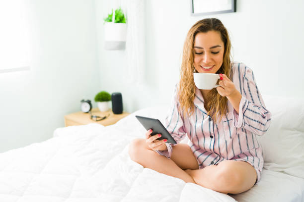 istock Cheerful woman drinking coffee and holding an e-reader 1312734558