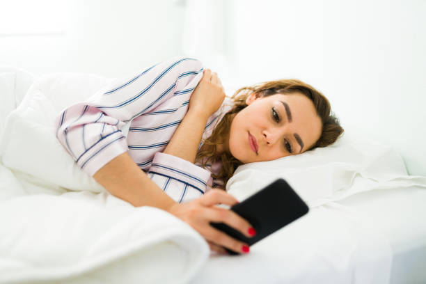 istock Tired young woman lying in bed and texting 1312734581