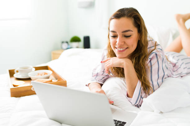 istock Happy woman smiling while working in bed with her laptop 1312734694