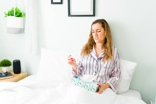istock Sad woman in pajamas using a thermometer 1312734701