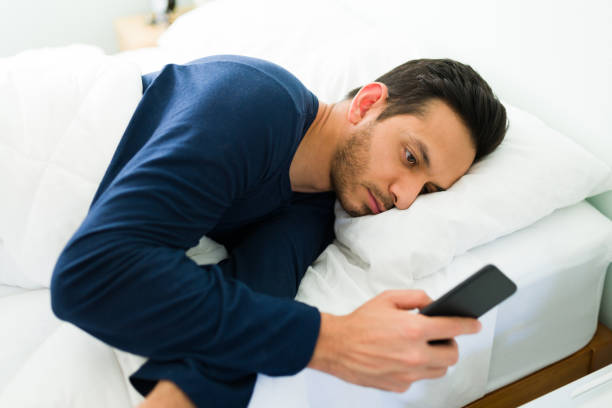 istock Tired young man lying in bed and texting 1312736407