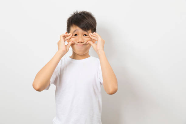istock happy asian boy makes funny face on white background. 1312737259