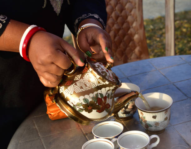 istock Pouring hot black tea from restaurant style cattle. Selective focused on kettle and poured tea. 1312738132
