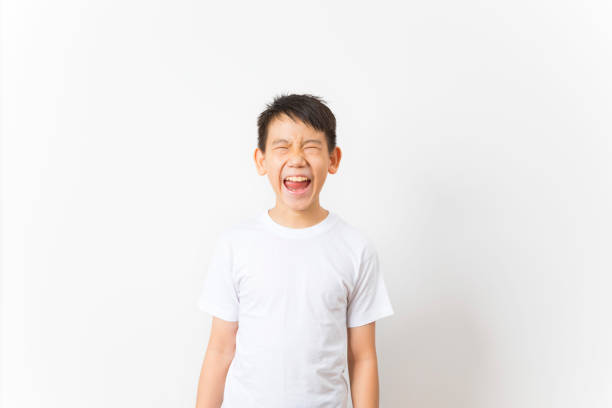 Portrait of a happy asian boy makes funny face on white background.