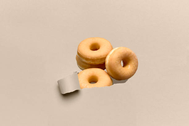 istock Delicious donut appearing through a broken cardboard. 1312743108