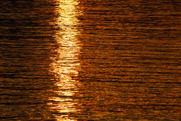 Natural sea background with large copy space. Dramatic sunrise over water. Multicolored surface with degradation. Reflection on waves. Tranquil and meditative view.