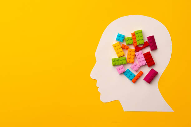 istock Papercut head silhouette with toy constructor pieces on yellow background 1312747224