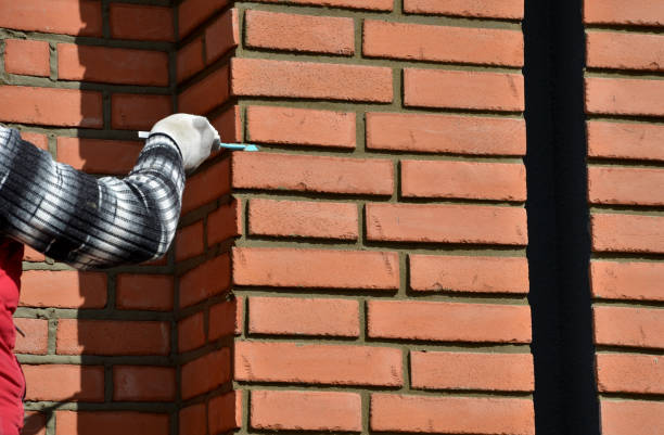 installation of fired brick cladding. installation of fired brick cladding. after gluing to the wall, the joints are filled with cement. the worker strokes with the help of a spatula every gap between the bricks. cladding construction equipment photos stock pictures, royalty-free photos & images