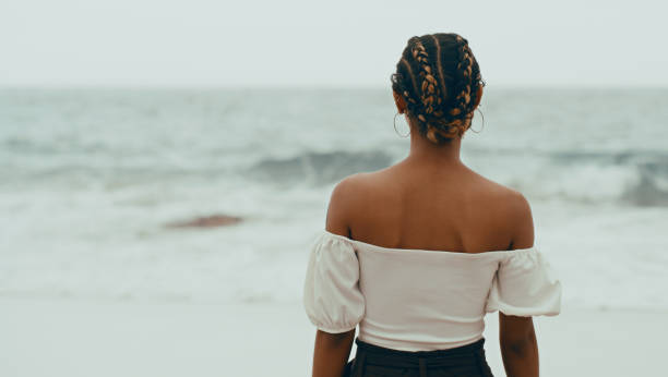 Cropped shot of an unrecognizable woman standing alone on the beach and looking out at the sea in contemplation