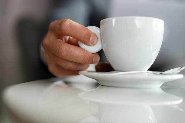 Close up of unrecognizable man holding white cup of coffee. Copy space.