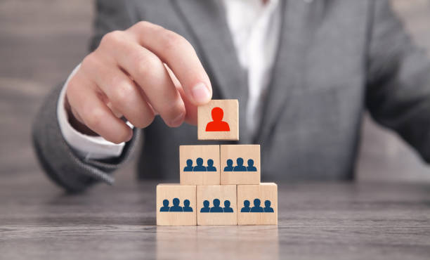 istock Male hand putting wood cube leader on pyramid. 1312752422