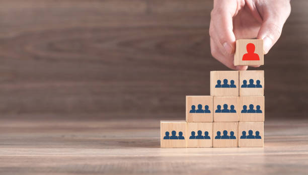 istock Male hand putting wood cube leader on pyramid. 1312752425
