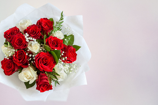 18 red roses arranged in a vase with greenery and misty blue