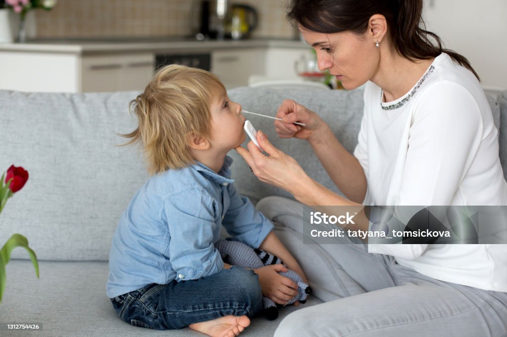 Mother, testing her child for covid at home, making home allowed swab tests Mother, testing her child for covid at home, making home allowed swab tests to prove negative result Coronavirus Stock Photo