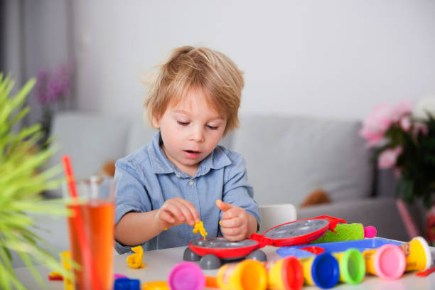 istock Cute blond child, boy, playing with play doh modeline at home, making different objects 1312755233