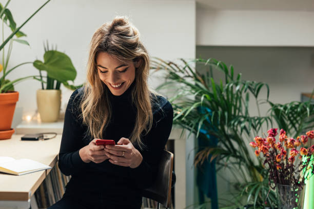 istock Young Caucasian Female Professional Working from Home- Sitting in her Office Area while Using Smartphone (Horizontal) 1312755459