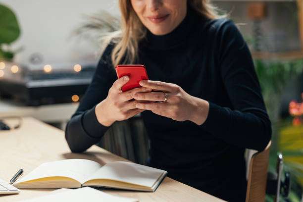 istock Unrecognizable Young Caucasian Female Professional Working from Home- Sitting in her Office Area while Using Smartphone (Horizontal) 1312755476